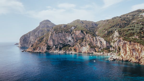 Stunning view of Corfu's coastal cliffs with crystal blue waters in a serene summer setting.